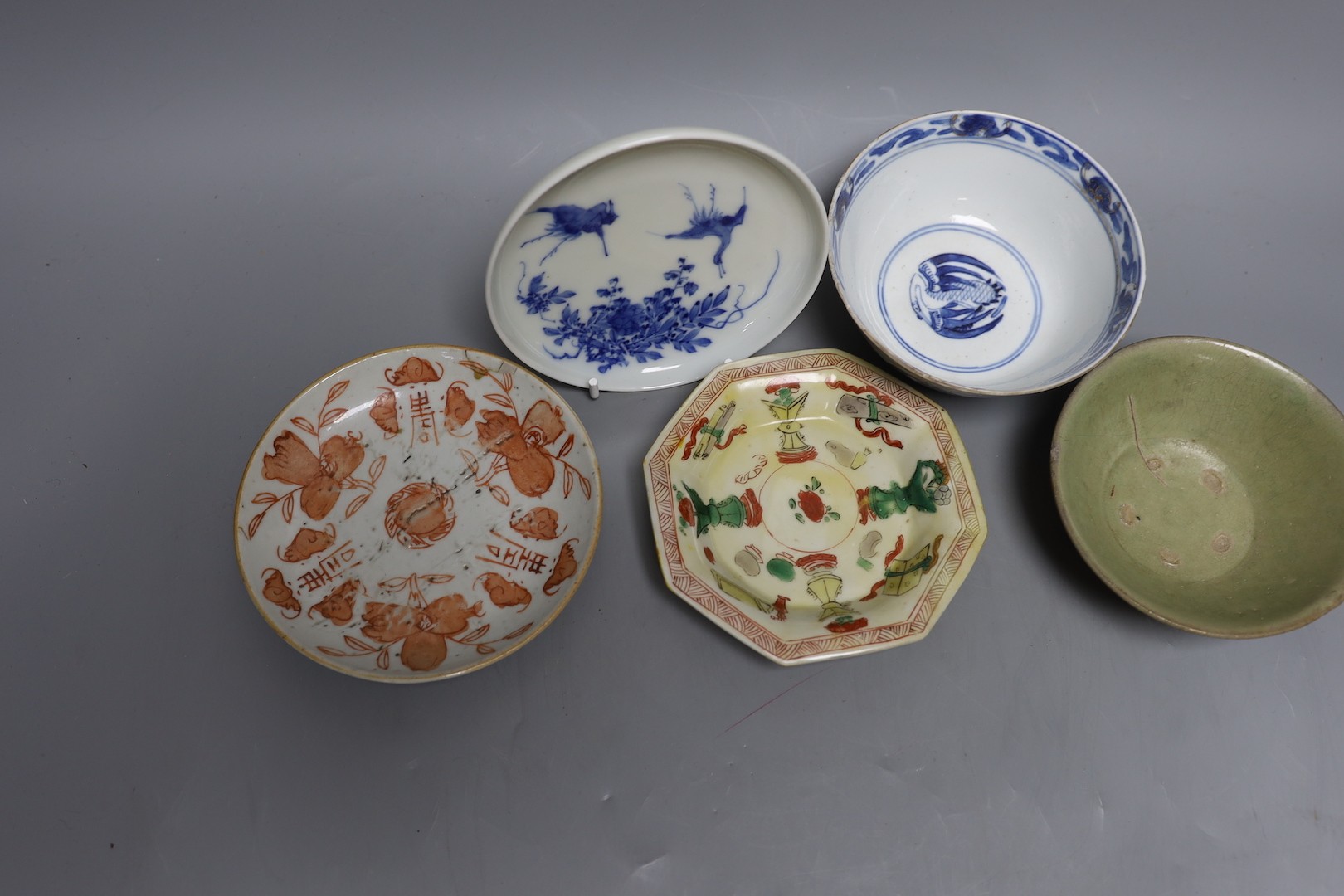 A Korean celadon bowl, a Chinese blue and white bowl, an iron red dish a famille Verte saucer and a Japanese blue and white saucer